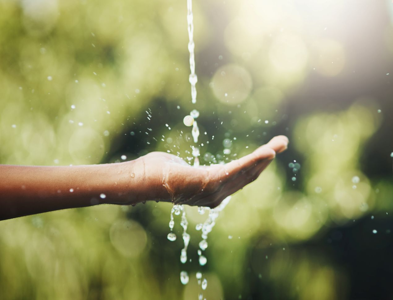 Eine Hand fängt Wasser aus einem fließenden Strahl auf – symbolisiert den bewussten Umgang mit Wasser durch nachhaltige Lösungen wie Trockentrenntoiletten.