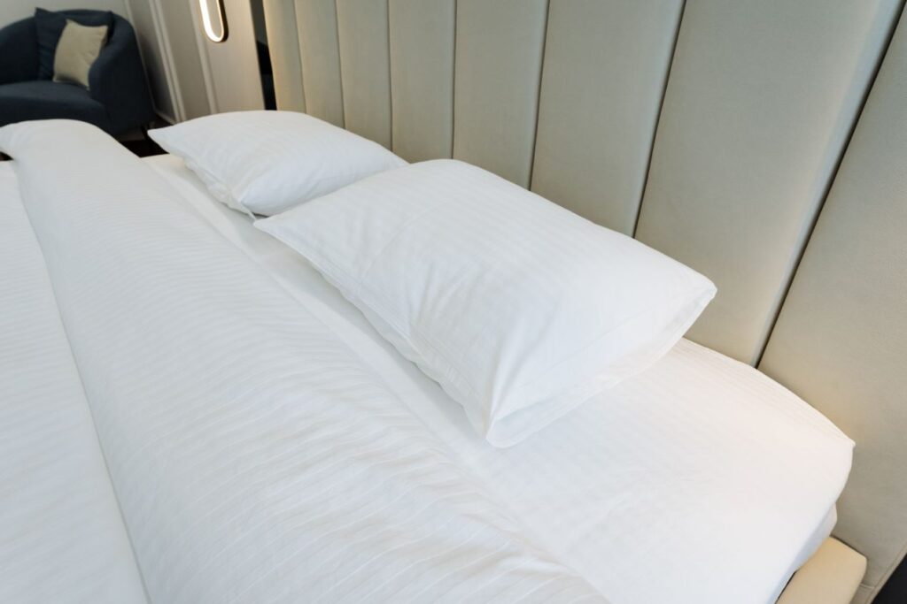 modernes Doppelbett mit weissem spannbettlaken 200x200 und Kopfteil in Designhotel