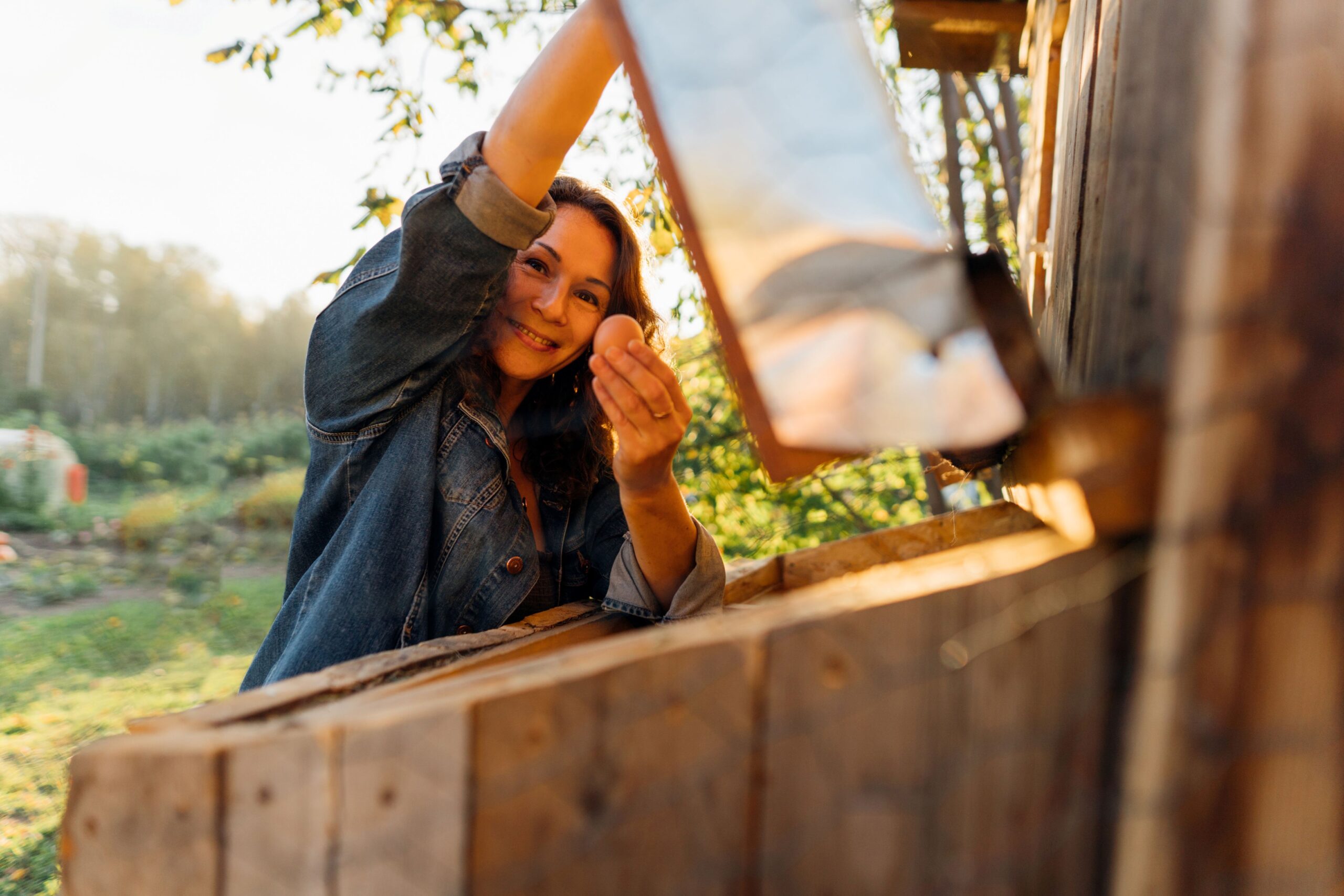 Frau öffnet Hühnerstall und zeigt Nähe zur natürlichen Haltung