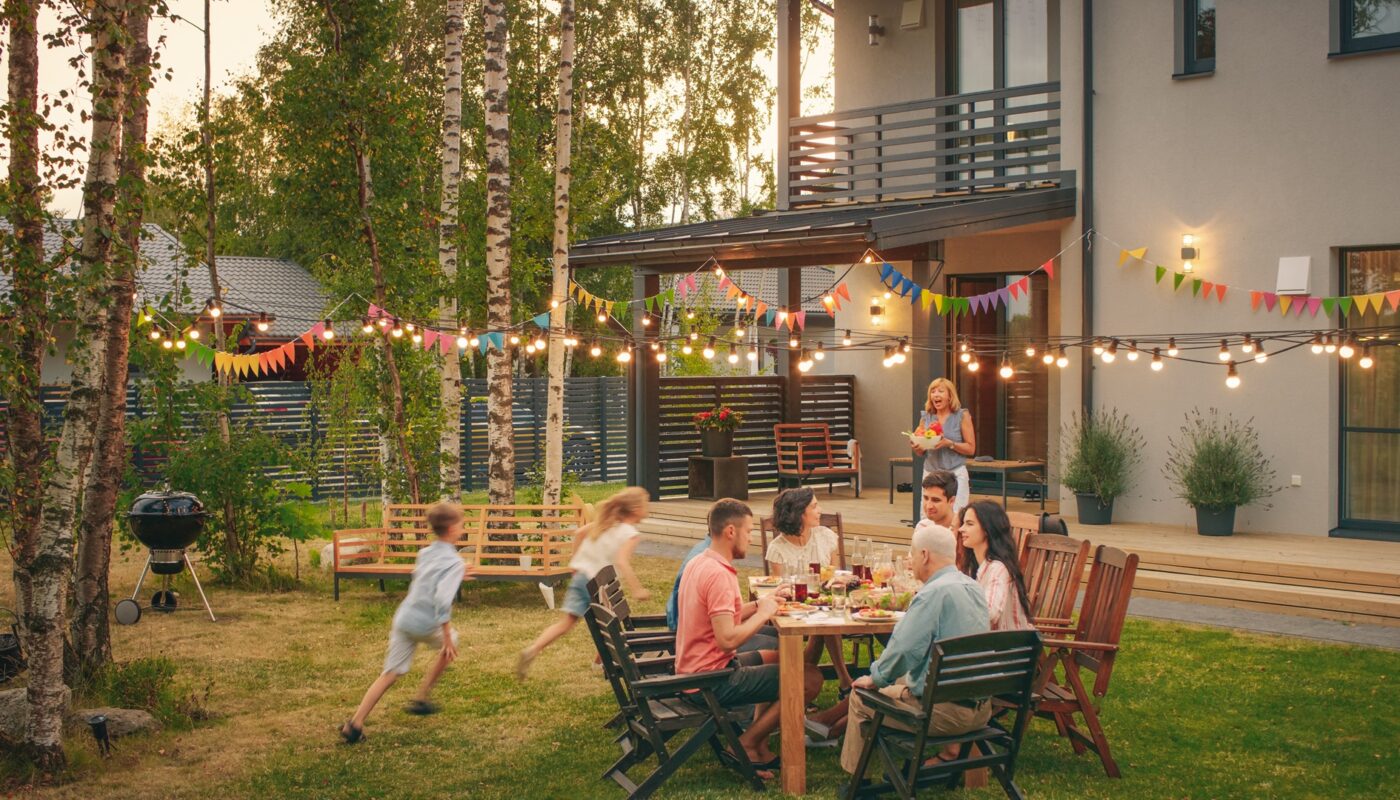 Familie sitzt im Garten bei Sommerfest mit Lichterketten und bunten Wimpeln | Cortenstahl Hochbeet