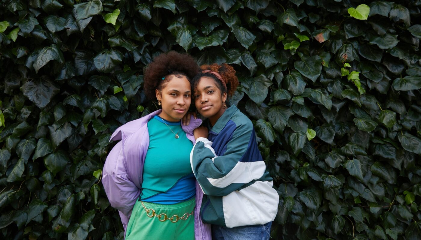 Zwei Frauen in farbenfrohen Outfits vor grüner Wand | Musselin Bluse