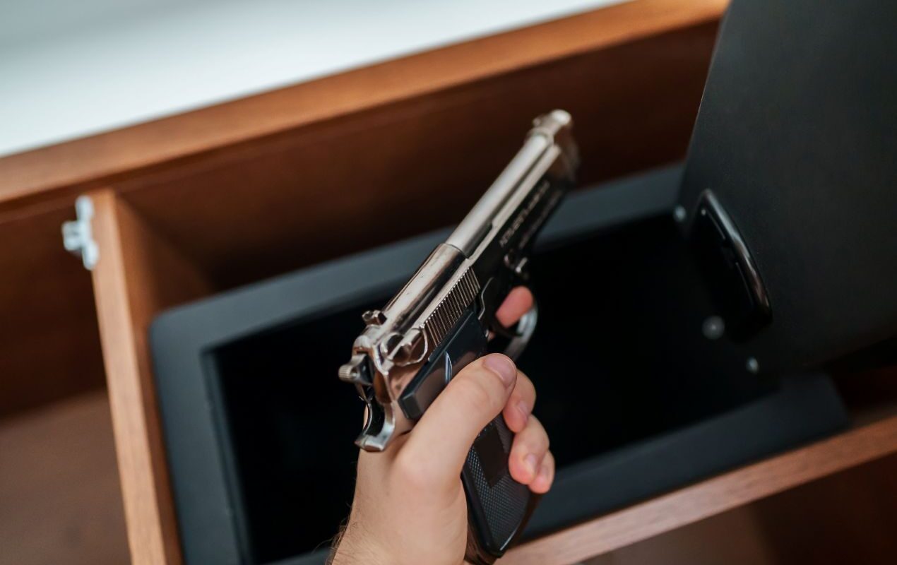 Hand legt eine Schreckschusspistole in einen abschliessbaren Tresor zur sicheren Aufbewahrung