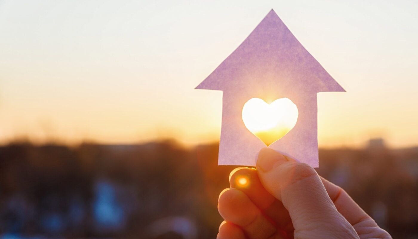 Hand hält Hausform mit Herz im Sonnenlicht | Brennholz Augsburg