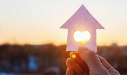 Hand hält Hausform mit Herz im Sonnenlicht | Brennholz Augsburg