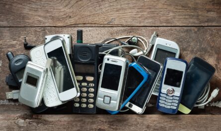 Haufen alter Handys mit Kabeln auf Holztisch | Handybörse